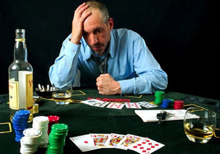 a Gambler at the Table with Cards and a Bottle